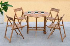 a wooden table with four chairs and a potted plant on the side walk way