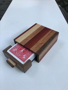 a wooden box sitting on top of a table next to a red and white playing card