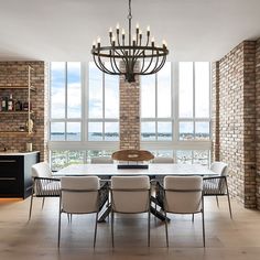 a dining room table with chairs and a chandelier in front of large windows