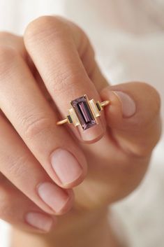 a woman's hand holding an amethorate ring