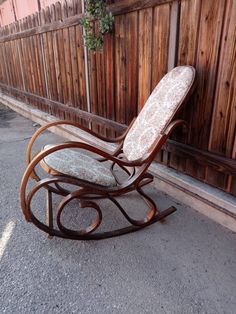 an old rocking chair sitting in front of a wooden fence