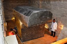 a man standing next to a large stone structure