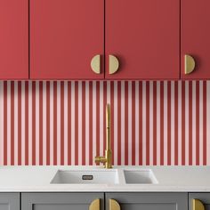 a kitchen with red cabinets and white counter tops, gold handles on the faucet