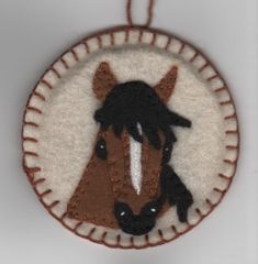 a felt ornament with a horse's head in the center on a white background