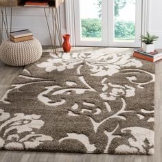 a rug with an ornate design on the floor in front of a window and bookshelf