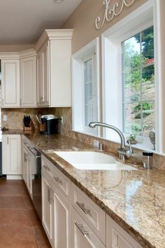 a kitchen with marble counter tops and white cabinets