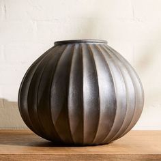 a large metal vase sitting on top of a wooden table