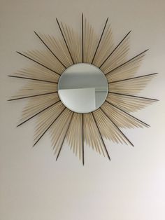 a mirror mounted to the side of a wall next to a white wall with a sunburst design on it