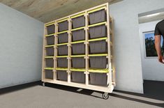 a man standing next to a shelf with bins on it's sides and yellow tape around the shelves