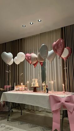 a table topped with lots of pink and white balloons