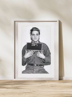 a black and white photo of a young man holding a laptop in front of his face