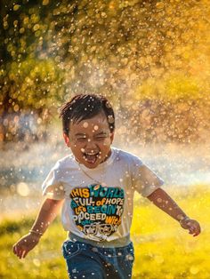 a young boy running through the rain with his face covered by water droplets and spray