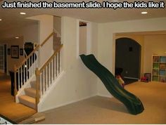 a slide in the middle of a living room next to a stair case and bookshelf