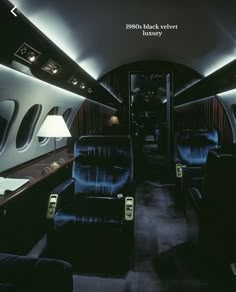 the inside of an airplane with blue seats and black velvet upholstered seating area