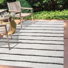 two wooden chairs sitting on top of a rug next to an outdoor table and chair