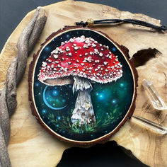 a painting of a red mushroom on a piece of wood next to some crystal beads