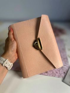 a woman holding onto a pink purse on top of a table