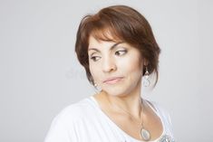 a woman in white shirt posing for the camera with her hand on her hip and wearing earrings