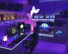 a desk with two monitors and a laptop on it in a room that has purple lighting