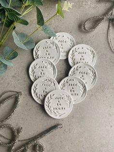 six white ceramic coasters sitting on top of a table next to scissors and greenery