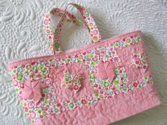 a pink purse sitting on top of a quilted tablecloth covered floor next to a white wall