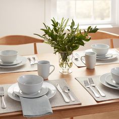 the table is set with white dishes and silverware