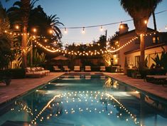 an outdoor swimming pool with string lights strung over it