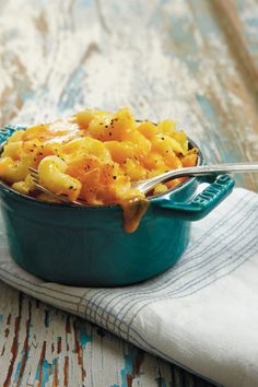 a blue dish filled with macaroni and cheese on top of a white towel