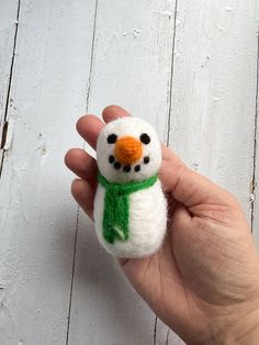 a hand is holding a small felt snowman