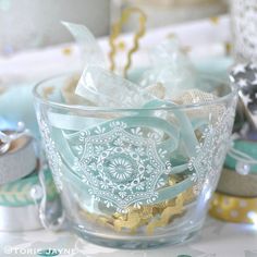 a glass bowl filled with decorative items on top of a white table covered in confetti