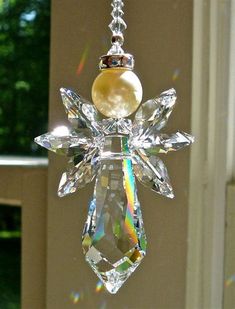 a crystal ornament hanging from a window with a pearl in it's center