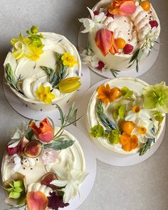 four cakes decorated with flowers on white plates