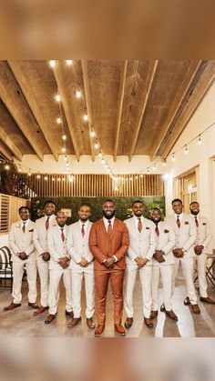 a group of men standing next to each other in white suits and orange ties,