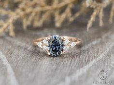 a blue and white diamond ring sitting on top of a piece of wood next to some branches