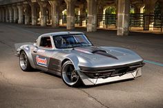 a silver sports car parked in front of an overpassed area with columns on either side