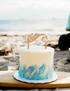 a cake sitting on top of a wooden board next to the ocean with a sign that says love