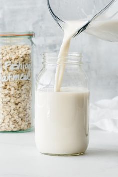 milk being poured into a glass jar filled with oatmeal