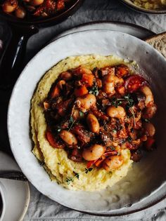 a white bowl filled with shrimp and grits on top of a table next to other dishes