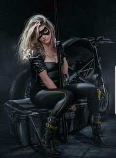 a woman sitting on top of a motorcycle with her legs crossed and wearing black boots