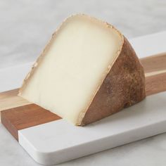 a piece of cheese sitting on top of a cutting board