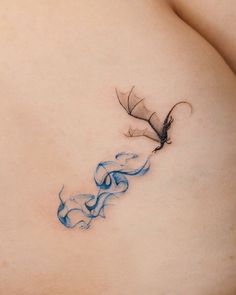 a woman's stomach with a blue and black tattoo design on the side of her breast