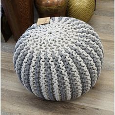 a round knitted poufce sits on the floor next to other decorative items