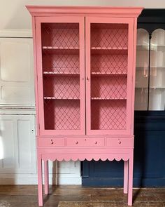 a pink china cabinet sitting on top of a hard wood floor