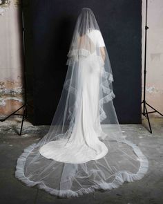 the back of a wedding dress on display in front of a photo studio backdrop with a mannequin wearing a veil