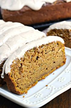 there is a loaf of carrot bread on the plate with frosted icing next to it