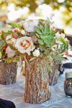 the centerpieces on this table are made from logs with flowers and succulents