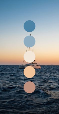 a sailboat floating on top of the ocean with circles hanging from it's mast