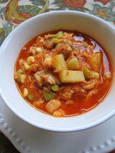 a white bowl filled with meat and vegetable soup