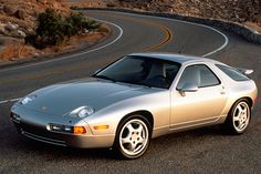 a silver sports car driving down a winding road