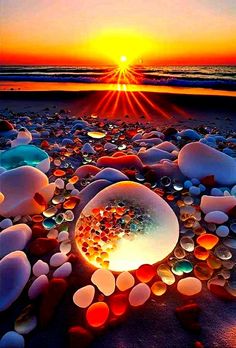 the sun is setting over some rocks and pebbles on the beach with water in it